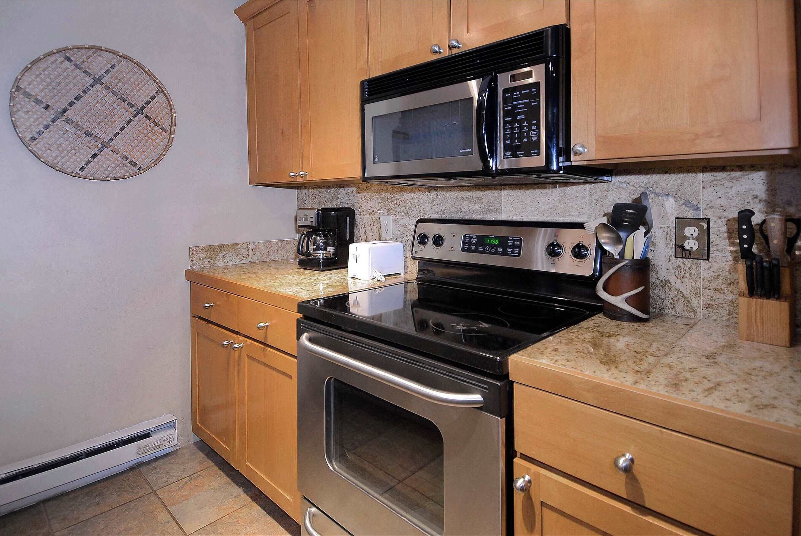 A kitchen with wooden cabinets, a stainless steel stove, a microwave, and a coffee maker.
