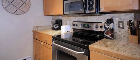 Una cocina con armarios de madera, una estufa de acero inoxidable, un microondas y una cafetera.