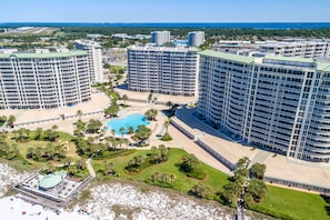 A high-rise hotel with multiple floors, a central swimming pool, and surrounding landscaped areas.