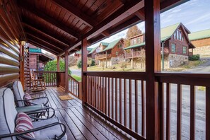 Une cabane en bois dotée d’une véranda, de meubles de jardin et offrant une vue sur les autres cabanes.