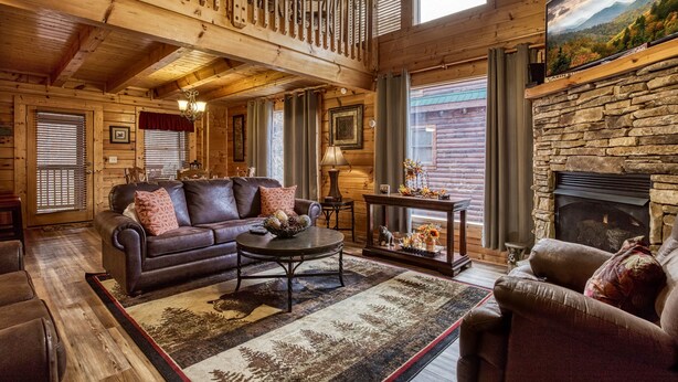L’intérieur d’une cabane en rondins, avec une cheminée, un canapé, une table basse et un lustre.