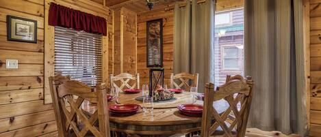 Comedor de madera con una mesa redonda, sillas y una araña.