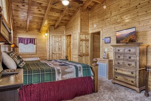 Une chambre de style rustique, avec un lit, une commode et un téléviseur fixé au mur.