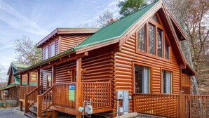 Une cabane en rondins avec un toit végétalisé, un revêtement extérieur en bois et une véranda avec des marches menant à l’entrée.