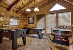 A wooden interior with pool tables and a foosball table.