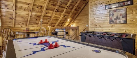A wooden-floored room with a foosball table, a bar area, and a wall-mounted sign indicating a 'GIRL ROOM'.