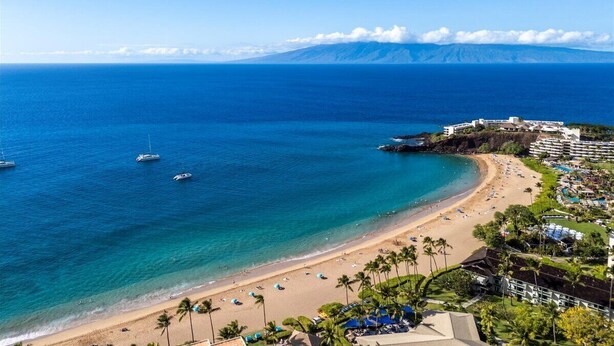 Una località balneare con spiaggia, oceano e montagne sullo sfondo.