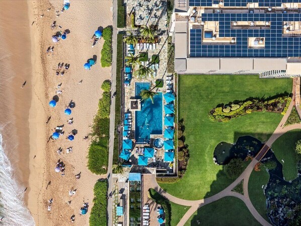 Vista aérea de un resort con piscina, playa y paneles solares.