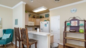 Una cocina con armarios de madera, un refrigerador blanco, un lavamanos y una pequeña isla con taburetes.