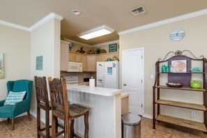 A kitchen with wooden cabinets, a white refrigerator, a sink, and a small island with stools.