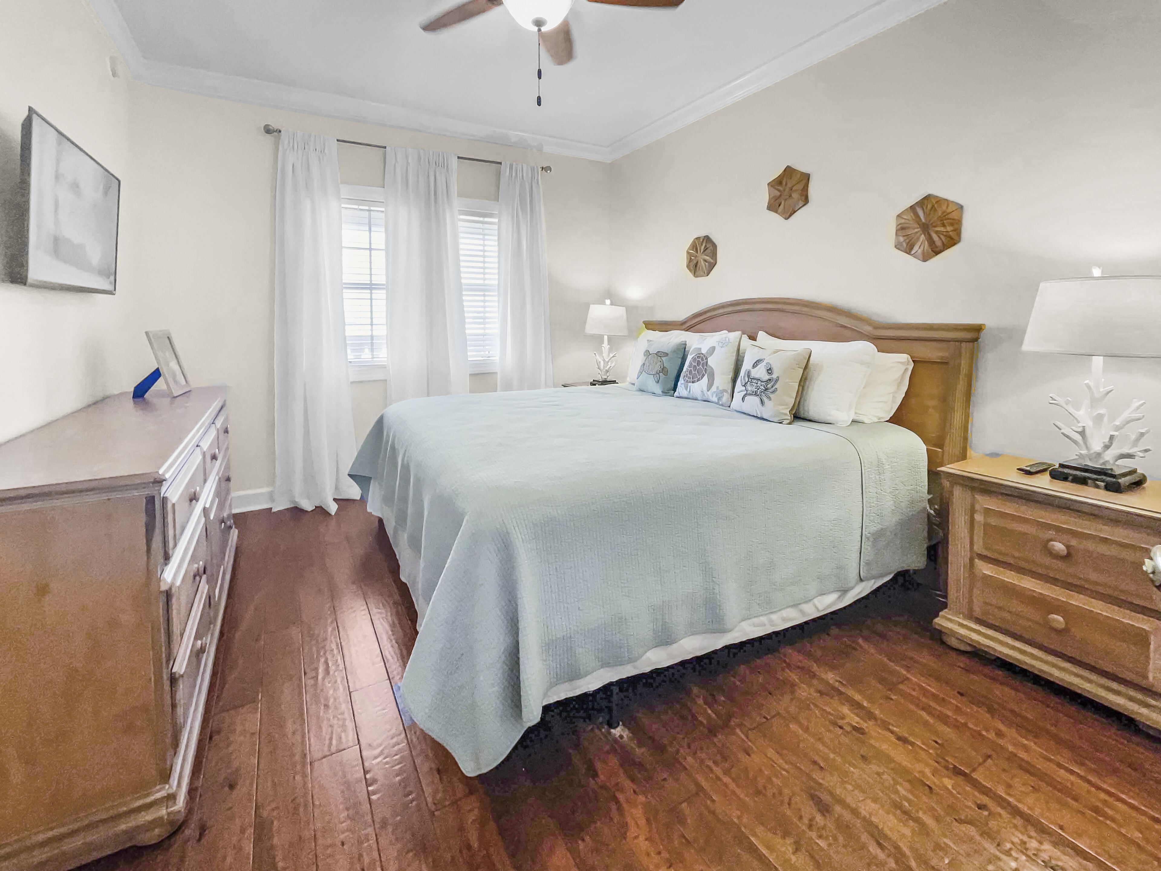 Un dormitorio con una cama de madera, una mesita de noche, un aparador y un ventilador de techo.