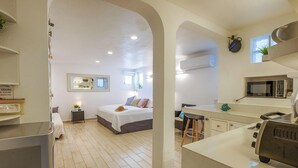 A compact, modern apartment with a bedroom, kitchenette, and a small dining area. - Steps to the sea! Charming garden view studio with beach access, WiFi and AC. (Akumal)