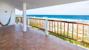A covered outdoor area with a view of the ocean, a hammock, and a wooden railing. - Oceanfront Akumal Villa With Pool Near Snorkeling & Restaurants (Akumal)