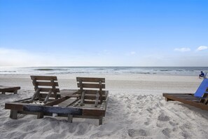 A beach with wooden benches and a blue lounge chair.