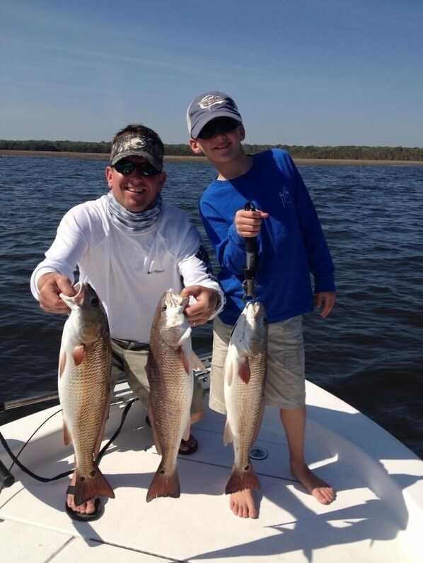 Two people on a boat holding fish.