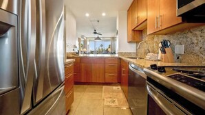 A modern kitchen with stainless steel appliances, wooden cabinets, and a granite countertop.
