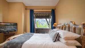 Een slaapkamer met een bed, een televisie en een raam met gordijnen.