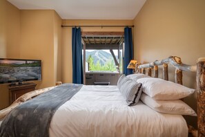 A bedroom with a bed, a television, and a window with curtains.