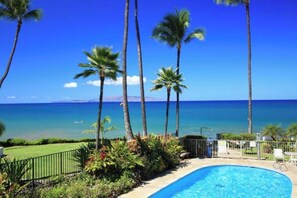 A swimming pool with a view of the ocean and palm trees. - Exceptional Location, Breathtaking Ocean View: Kamaole Nalu #204 (Kihei, Maui)