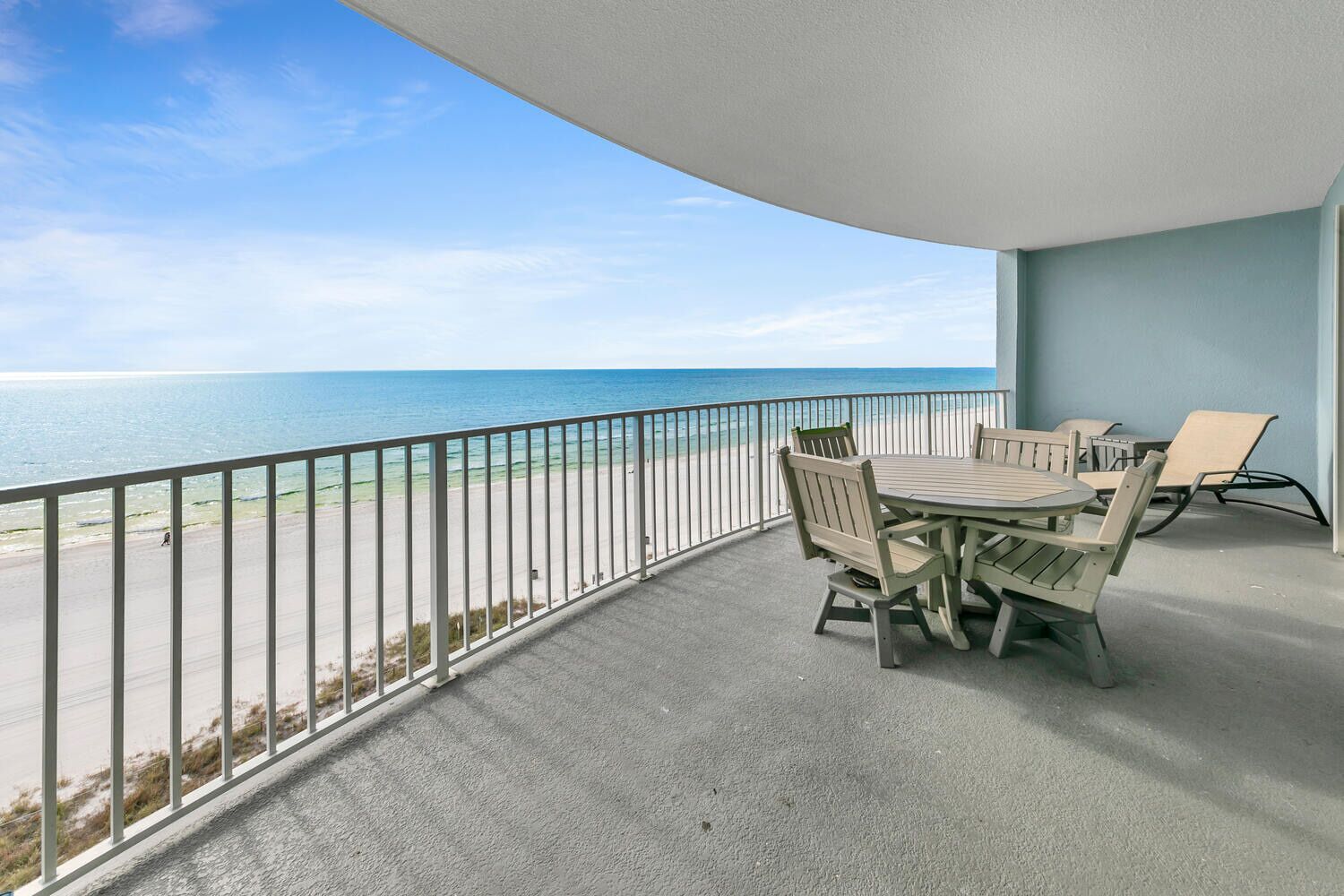 Ein Balkon mit Tisch und Stühlen mit Blick auf einen Strand und den Ozean.