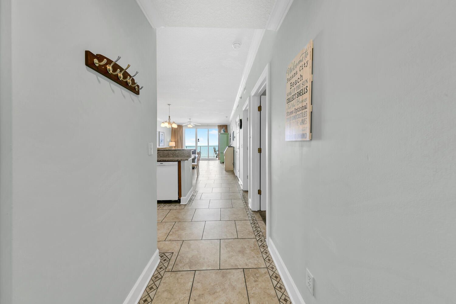 A hallway with a kitchen area, a dining area, and a view of the ocean.