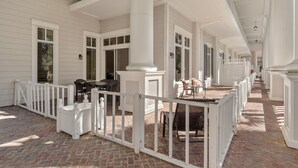 A covered outdoor area with white railings, brick flooring, and multiple seating areas. - Poolside Condo w/ GOLF CART! Tram to Beach. Steps to Pool and Baytowne Wharf! (Miramar Beach)