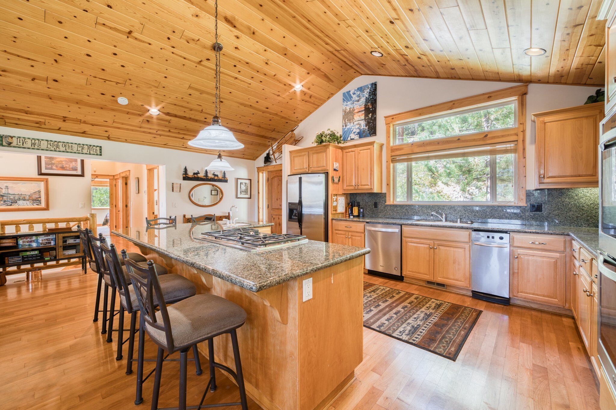A spacious kitchen with wooden cabinets, a granite countertop, and a large island with bar stools.