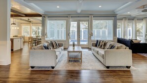 A spacious living room with a large sofa set, a coffee table, and a view through large sliding glass doors to the outside. - 52 N. Forest Beach-4th row (176 yard walk) to  ocean w/ elevator & much more! (Hilton Head Island)