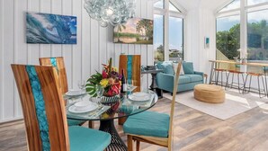 A dining area with a glass table, teal chairs, and a view of the outdoors.