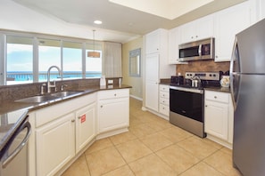 A kitchen with white cabinets, a stainless steel refrigerator, a microwave, and an oven.