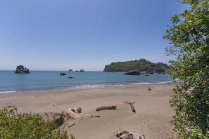 Una playa con agua azul cristalina, rocas dispersas y una colina distante cubierta de vegetación.