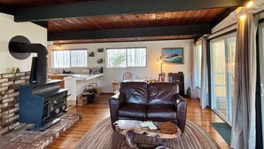 Een gezellige woonkamer met een leren bank, een open haard en een eethoek met een tafel en stoelen.
