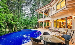 Un área de piscina exterior lujosa, con zona de comedor y terraza cubierta.
