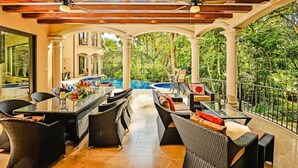 A covered outdoor dining area with wicker furniture, a pool, and a view of the surrounding greenery. - Luxury Home, Casa Vista Paraíso, Pool, Rainforest View, Access to Amenities. (Puntarenas)