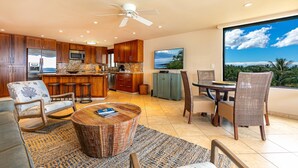 Una cucina moderna con mobili in legno, un'isola grande e un'area pranzo con vista sull'oceano.