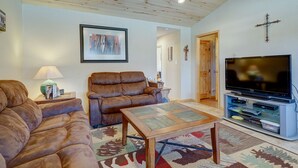 Una sala de estar con sofá, mesa de centro, televisor y techo de madera.