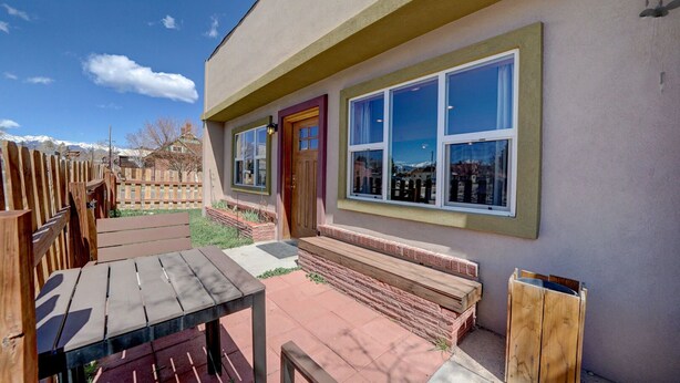 Un edificio residencial con terraza de madera, puerta principal y ventanas grandes.