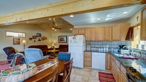 Una cocina compacta con muebles de madera, un refrigerador y un comedor con mesa y sillas.