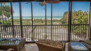 A balcony with wicker furniture, a ceiling fan, and a view of the beach.