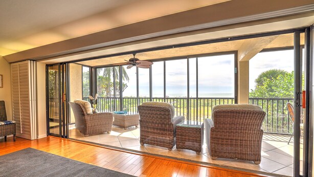 A spacious balcony with wicker furniture and a view of the ocean.