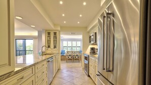 A spacious kitchen with a large stainless steel refrigerator, granite countertops, and a dining area with a wooden table and chairs.