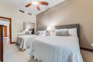 Une chambre d’hôtel avec deux lits, un ventilateur de plafond et un grand miroir.