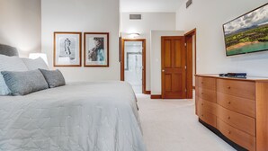 A bedroom with a bed, a dresser, and two framed pictures on the wall.