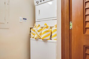A laundry area with a white dryer and a wall-mounted thermostat.