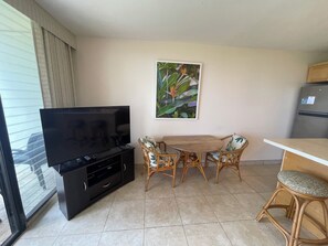 A living room with a TV, a dining table, and chairs. - Waiohuli Beach Hale #D-127 Direct Oceanfront Complex in Kihei, Steps to Beach (Kihei)
