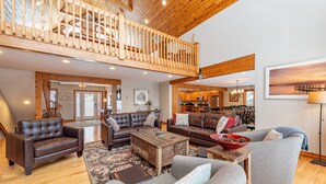 A spacious living area with a high ceiling, wooden beams, and a balcony. - Magical Lake Escape w/ Dock Slip & Game Room (Oakland)