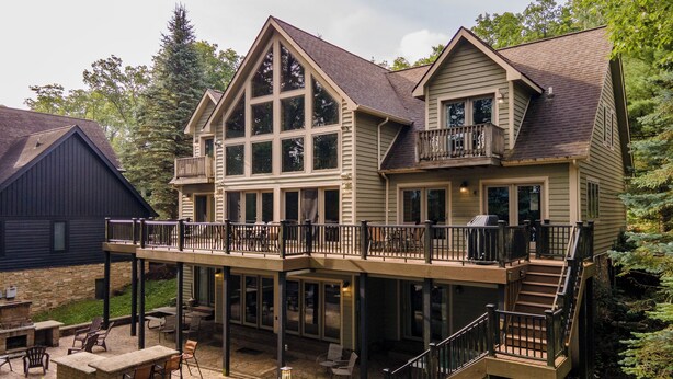 A two-story house with a balcony, outdoor seating area, and a stone fireplace. - Magical Lake Escape w/ Dock Slip & Game Room (Oakland)