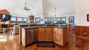 A spacious kitchen with wooden cabinets, a large island, and a ceiling fan.