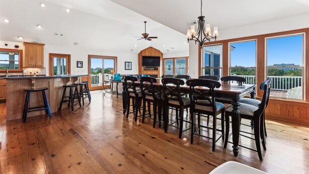 A spacious kitchen with a large island, wooden flooring, and a view of the outdoors.