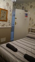 Een hotelkamer met een bed, een kaptafel, een spiegel en een deur met een branddeurpictogram.